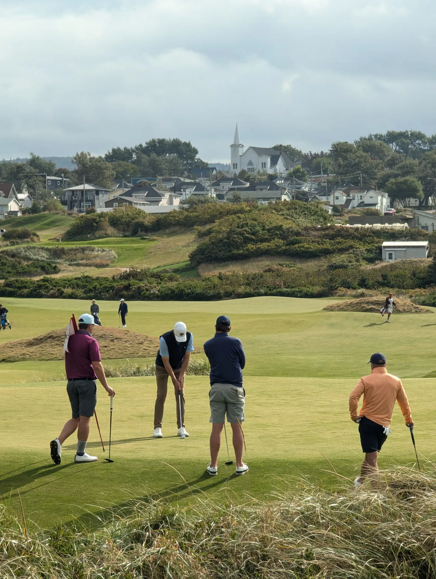 Golfers playing on a coastal course near a small town